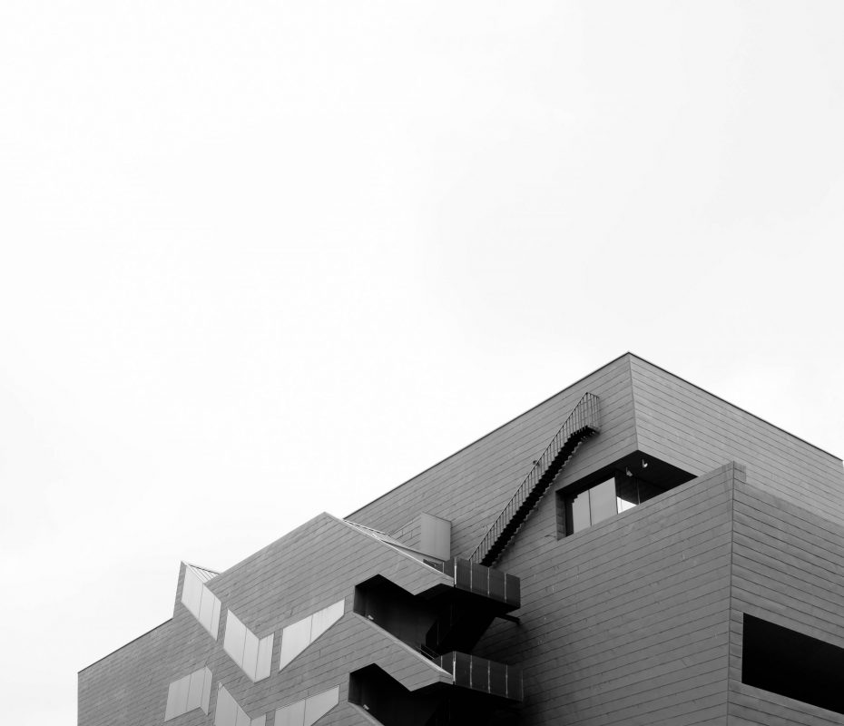 A low angle greyscale shot of a concrete modern building isolated on a white background